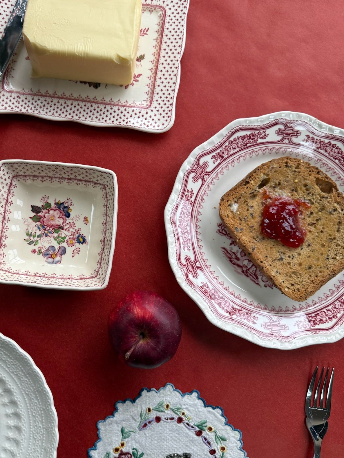 Assorted ceramic plates with food on a red tablecloth