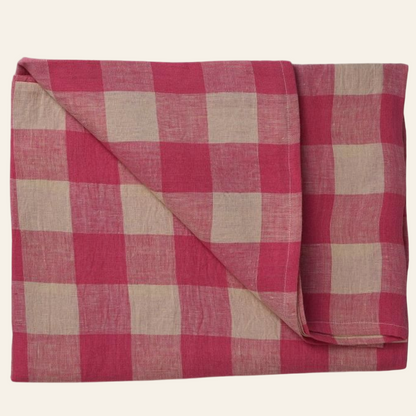 A folded pink and beige checkered linen table cover.