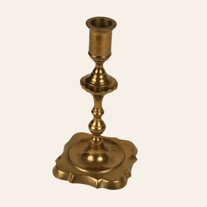 A vintage brass candle holder with a scalloped base and a polished finish.