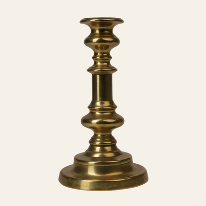 A vintage brass candle stand with a turned column and a weighted round base, featuring a polished brass finish.