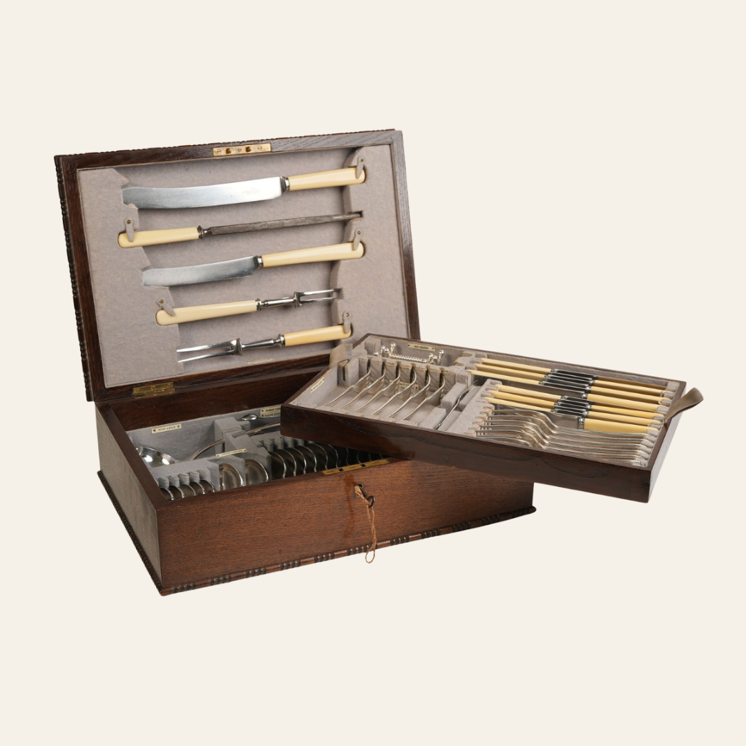 Set of antique knives and forks in a wooden case on a white background