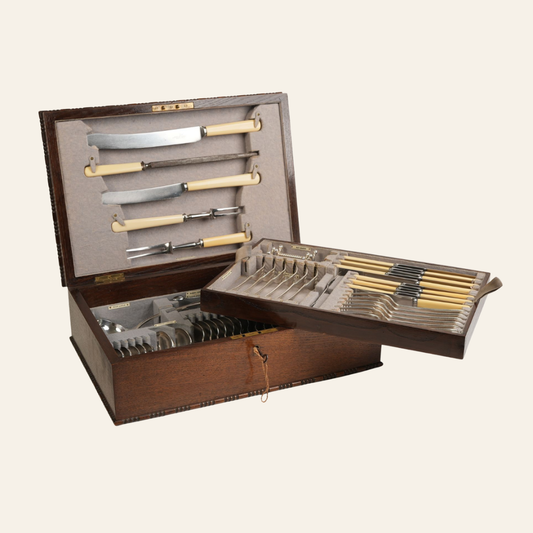 Set of antique knives and forks in a wooden case on a white background