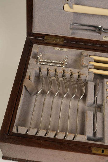 Set of silver forks and knives in a wooden case with gray interior