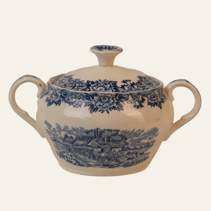 A vintage sugar bowl with blue and white floral transferware design, featuring a classic knob handle on the lid and two handles on the side.