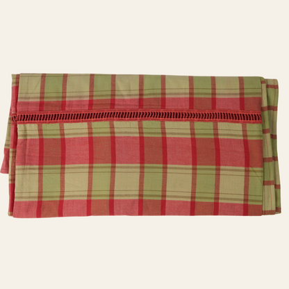 A folded red and green checkered table cover on a plain background.
