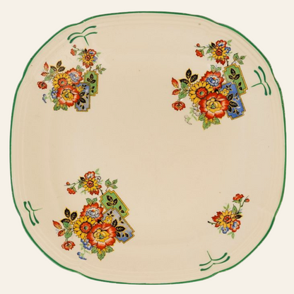 A round, vintage floral serving plate with a green border and colorful floral patterns in the center.