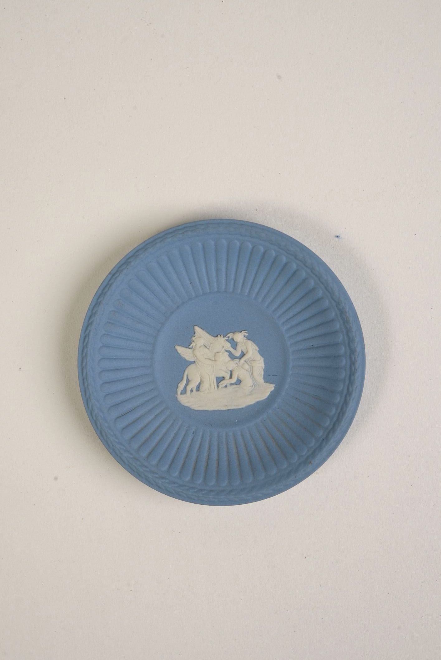 Blue ceramic plate with white relief design on a light gray background