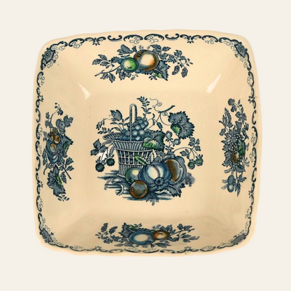 Antique square ironstone bowl with a central blue Fruit Basket pattern featuring a woven basket overflowing with grapes, peaches, and plums, surrounded by floral motifs.