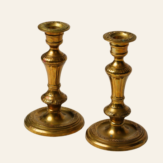 Two ornate antique brass candlesticks on a white background