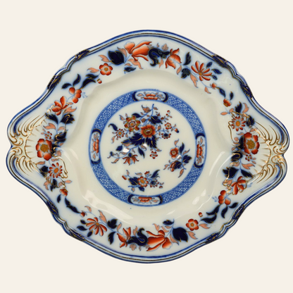 A Victorian ceramic platter with a central floral medallion, surrounded by a pattern of hand-painted sprays in orange and navy, with fine gold flourishes along the scalloped rim.