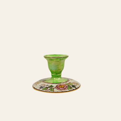 Green candle holder with floral design on a white background