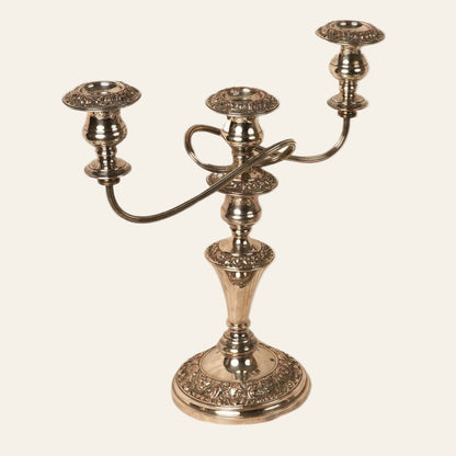 A three-armed Old Sheffield silver candelabra with intricate floral details and a reflective metallic finish.