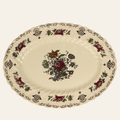 A vintage oval serving plate with a central floral bouquet design, surrounded by a border featuring traditional English florals in earthy tones.