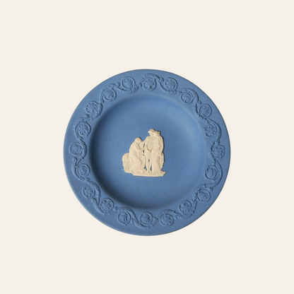 Blue ceramic plate with decorative edge and central figure on a white background