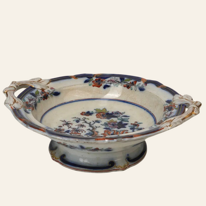 An antique Chinese tree pedestal fruit bowl with a floral pattern in blue, orange, and gold colors, featuring dual handles and a pedestal base.