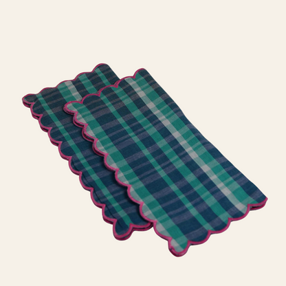 Set of three plaid placemats with scalloped edges on a white background