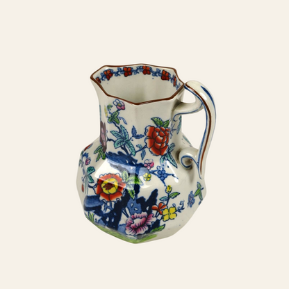 Decorative ceramic pitcher with floral and butterfly design on a white background