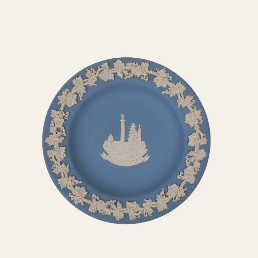 A vintage Wedgwood Jasperware small plate with a matte blue finish and intricate white reliefs, featuring a classical scene in the center.